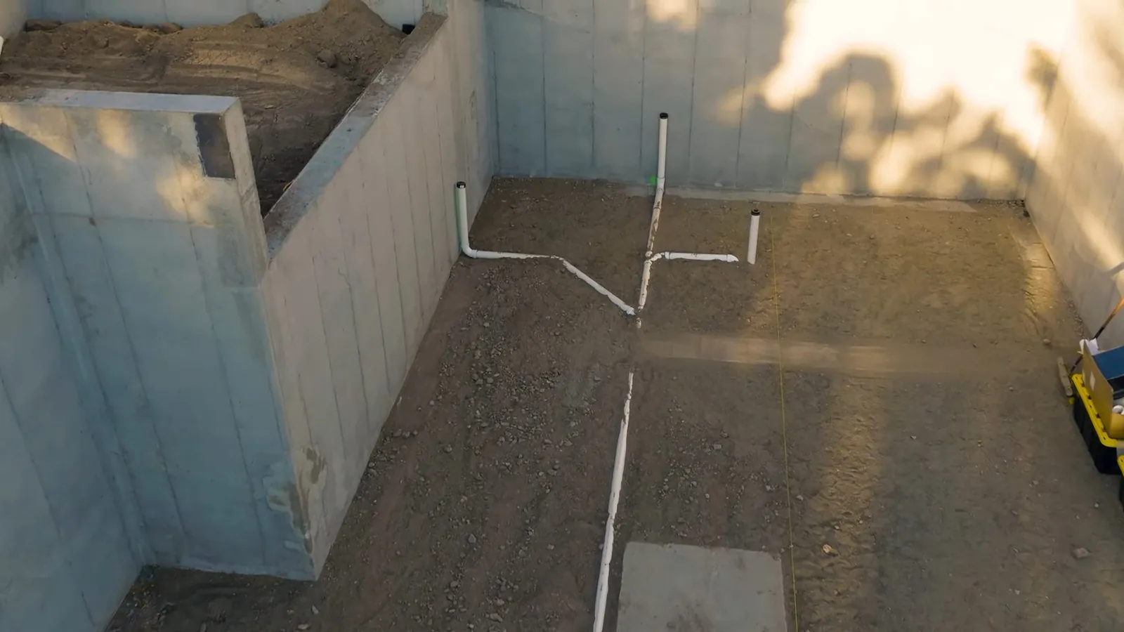 Interior drain line installed beneath a basement wall's wood framing