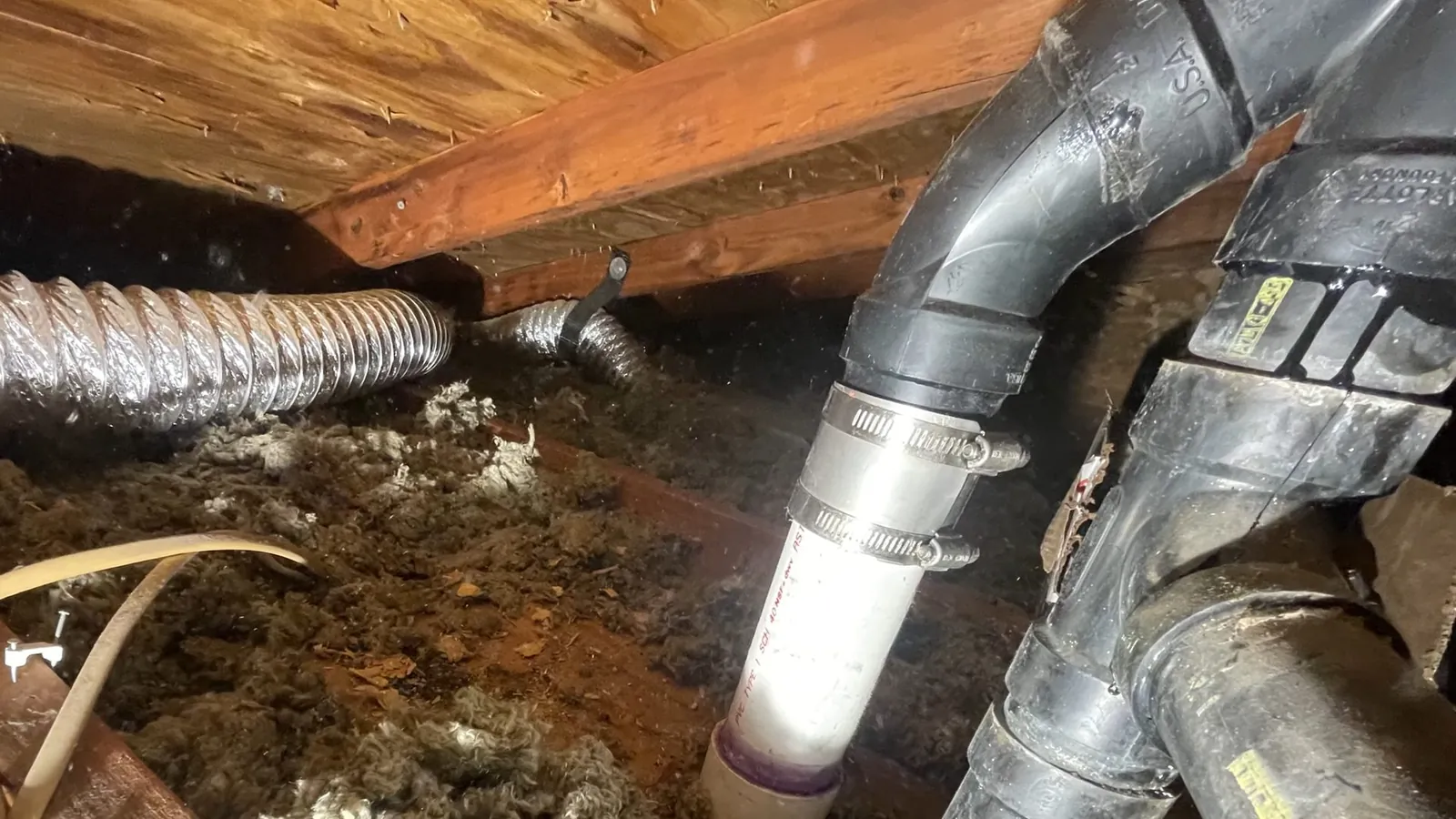 Drain and vent pipe routed beneath a basement subfloor
