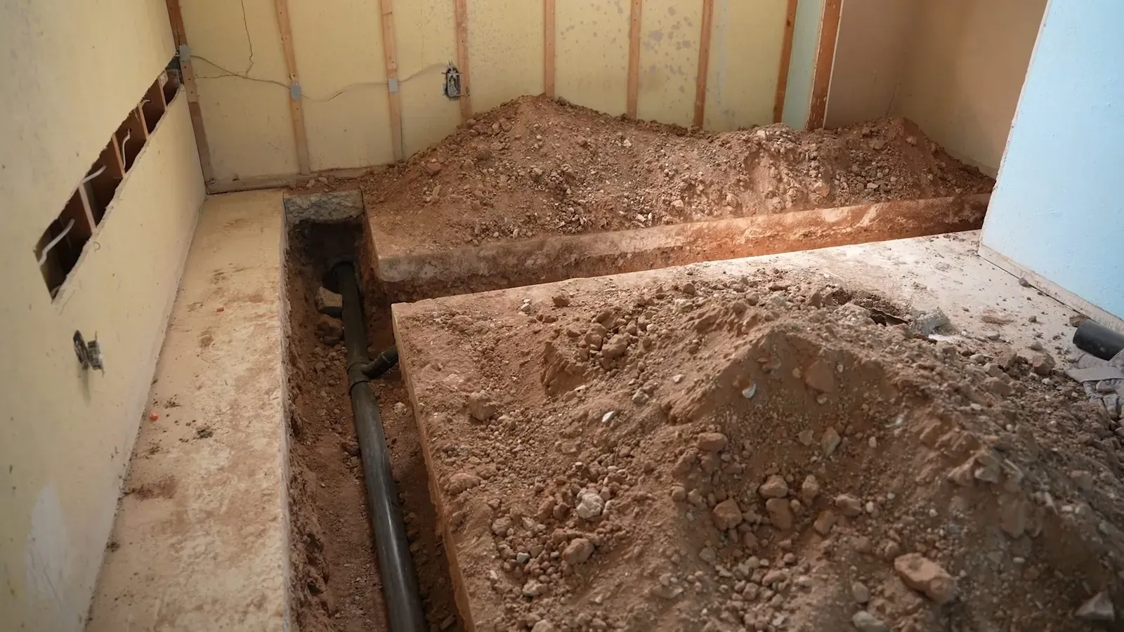 Basement floor excavated to expose a pipe for repair