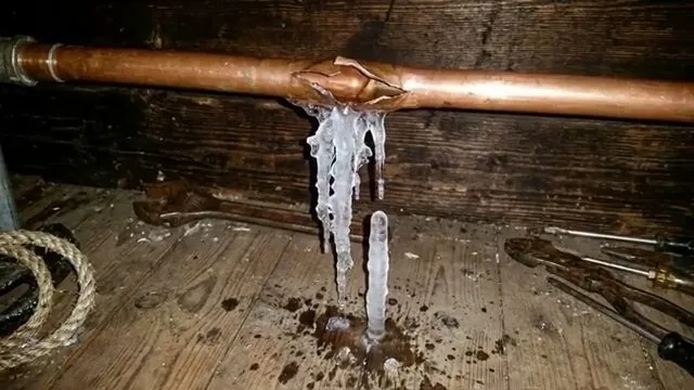 Burst copper pipe with ice still clinging to the split