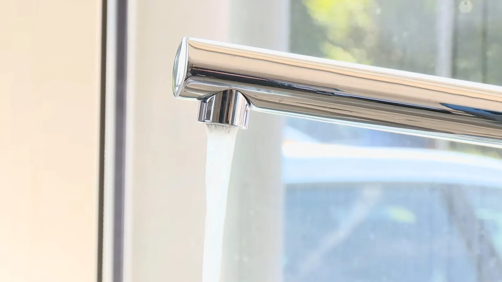 New chrome kitchen faucet installed beside a window