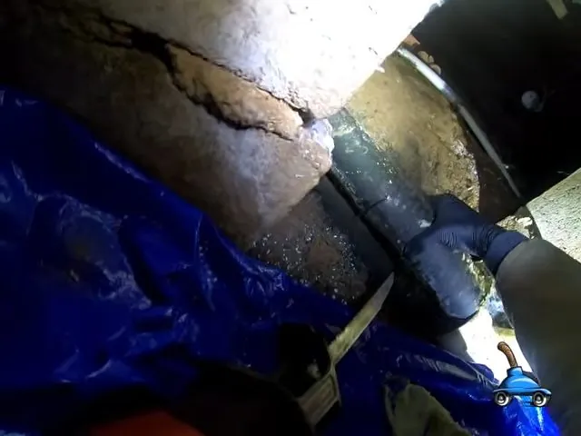 Plumber cutting out a damaged section of pipe in a crawlspace