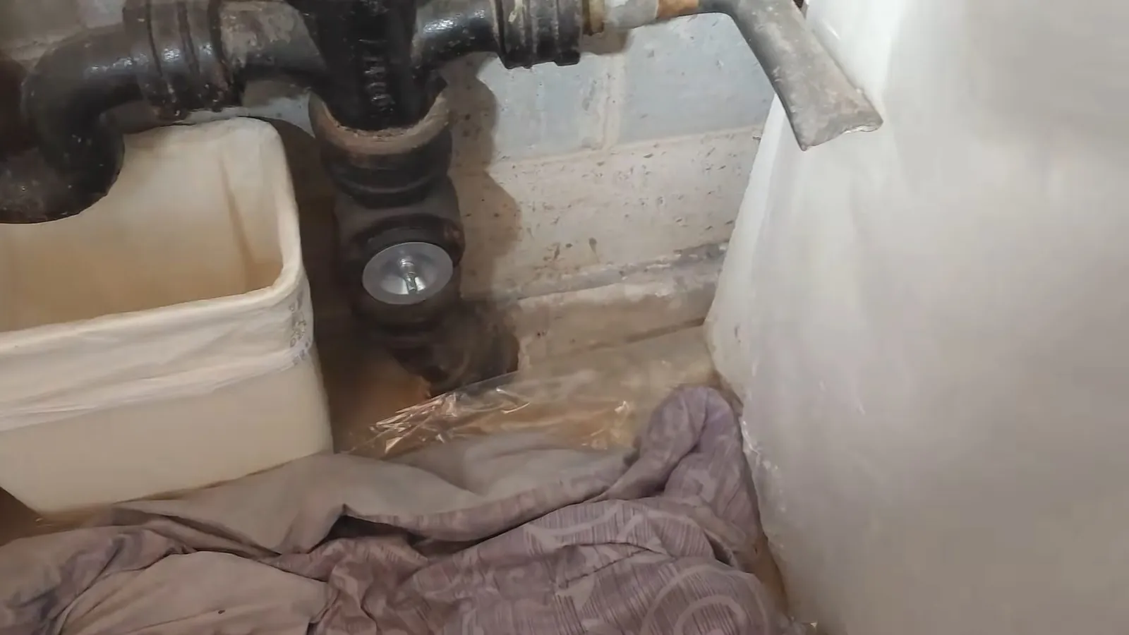 Damaged cast-iron drain exposed at a bathroom floor