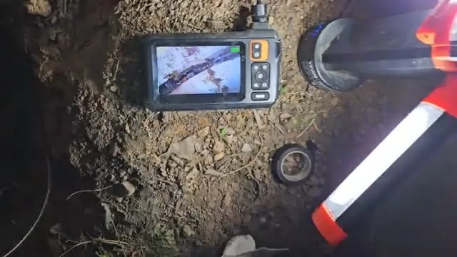 Sewer camera inspection monitor reviewed at an excavation site