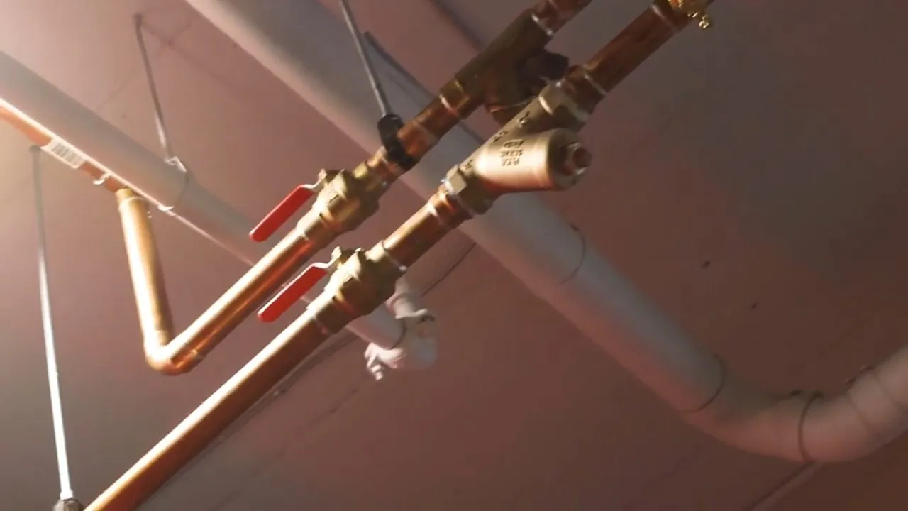 Plumbing rough-in exposed in a gym ceiling