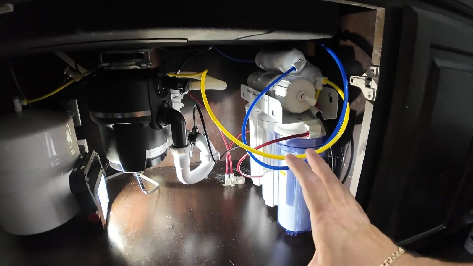 Garbage disposal wiring exposed inside a sink cabinet