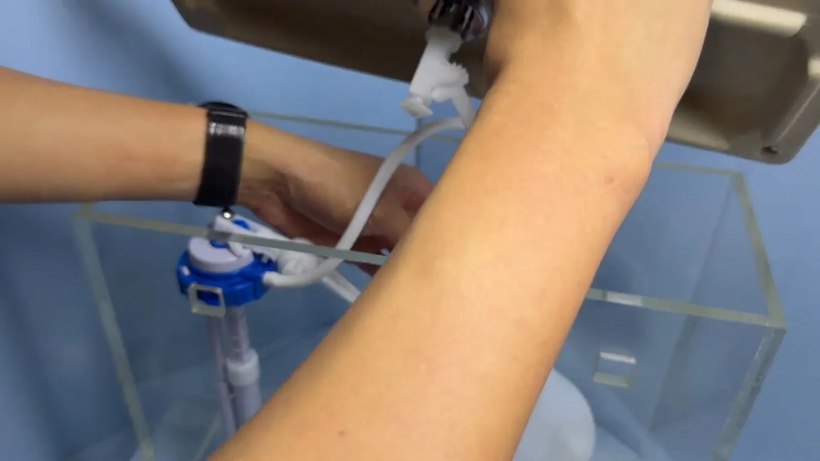 Hand adjusting a toilet fill valve inside the tank