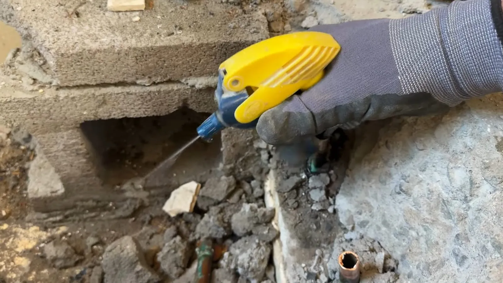 Plumber breaking a bathroom tile floor for access