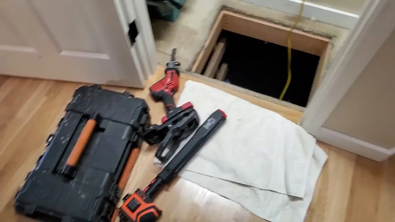 Plumbing tools staged beside an open floor access panel
