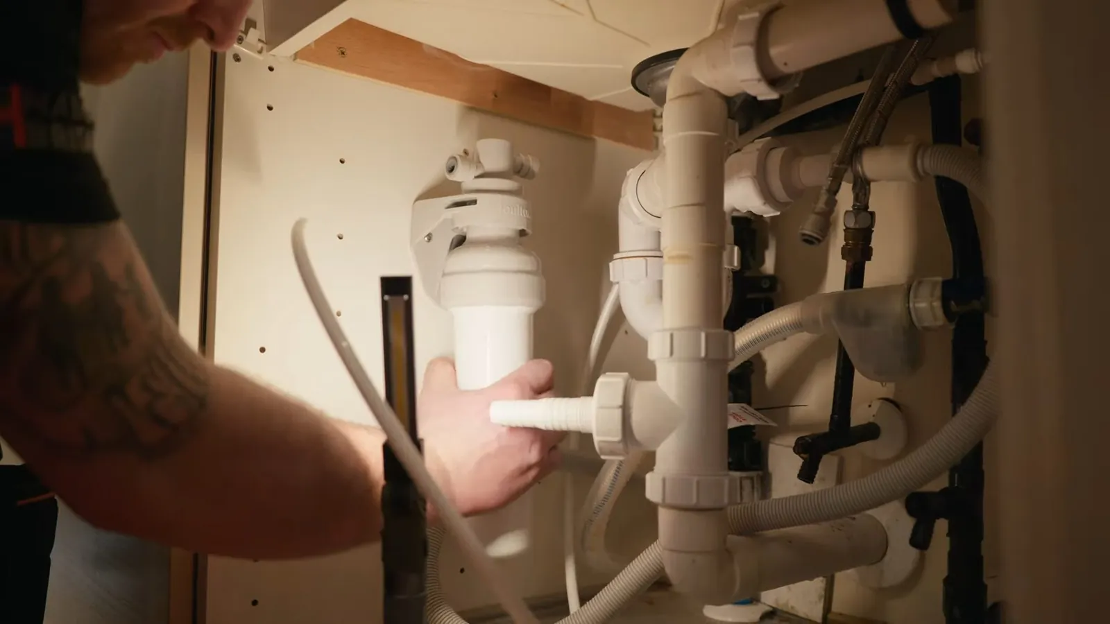 Technician fitting filter tubing beneath a kitchen sink